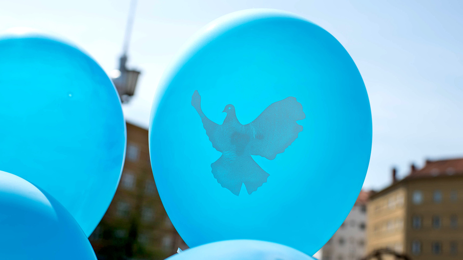 Blaue Luftballons mit aufgedruckter weißer Friedenstaube