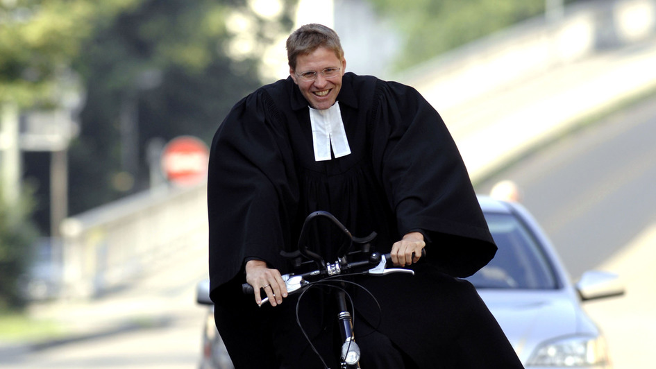 Ein Pfarrer im Talar fährt Fahrrad