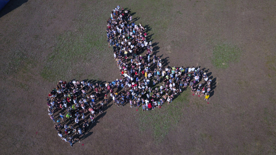 Luftaufnahme der teilnehmer eines KonfiCamps, die sich in Form einer Friedenstaube aufgestellt haben