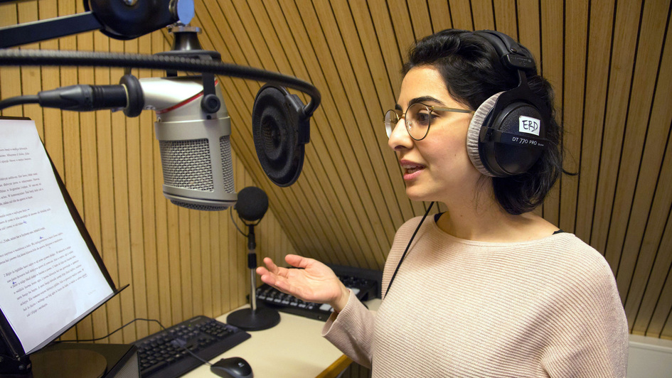 Eine junge Lehrerin im Tonstudio, sie spricht einen Märchentext in aramäischer Sprache ein