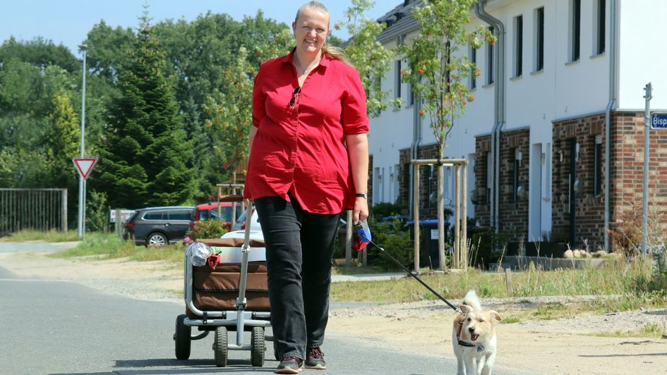 Pastorin Sabine Ulrich mit Missionshund Schepsi und Bollerwagen auf der Straße in Stade