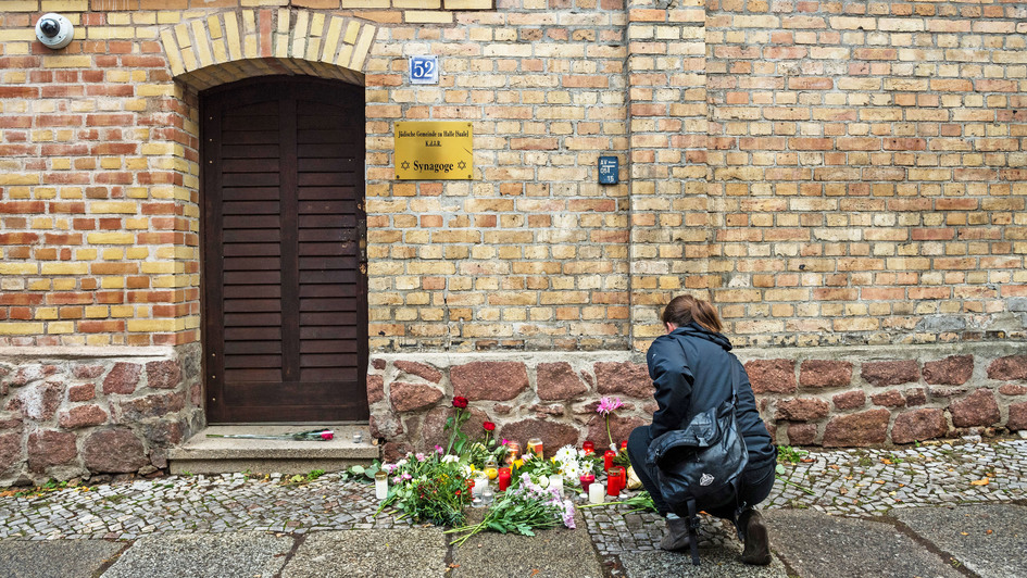 Eine Frau legt Blumen nieder vor Tür der Synagoge in Halle, die am 10. Oktober angegriffen worden ist