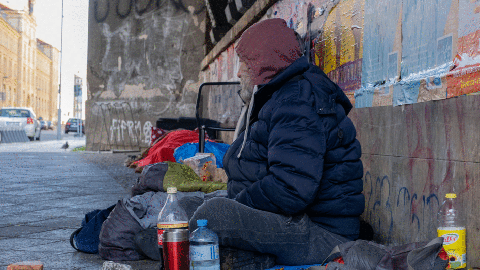 Obdachloser sitzt auf mit seinen Habseligkeiten auf der StraßeS