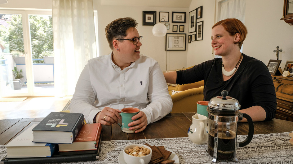 Das Pastorinnen-Ehepaar Stefanie und ellen Radtke in seinem Wohnzimmer. Die beiden betreiben den Youtube-Kanal 'Anders Amen'.