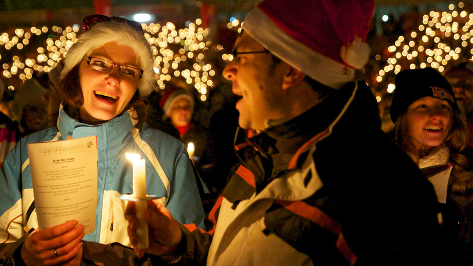 Menschen mit Kerzen singen Weihnachtslieder