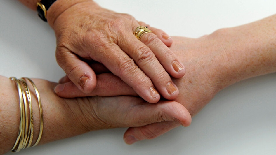Sterbebegleiterin in einem Hospiz hält die Hand einer Patientin Sterbebegleiterin in einem Hospiz hält die Hand einer Patientin