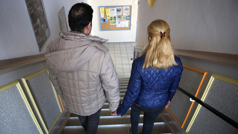 Mann und Frau gehen eine enge Treppe hinunter Mann und Frau gehen eine enge Treppe hinunter