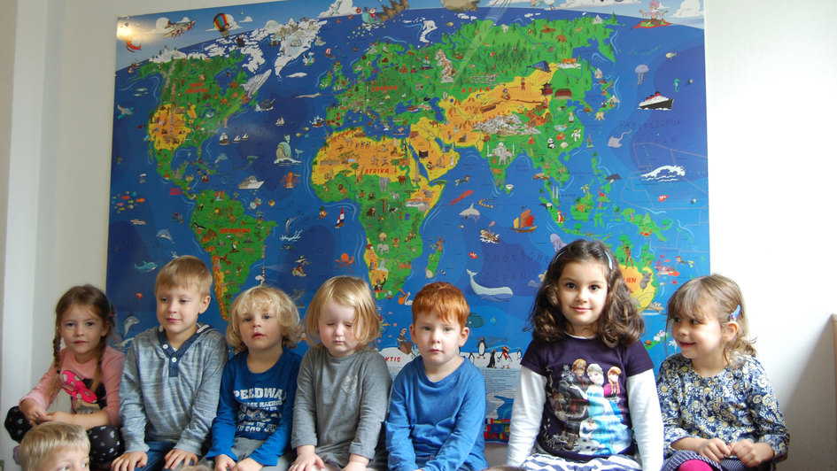 Kinder in Kita vor einer Weltkarte