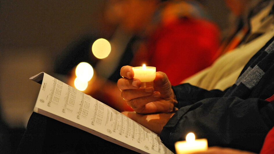 Gottesdienstteilnehmer halten Kerzen während eines Friedensgottesdienstes in der Hand Gottesdienstteilnehmer halten Kerzen während eines Friedensgottesdienstes in der Hand