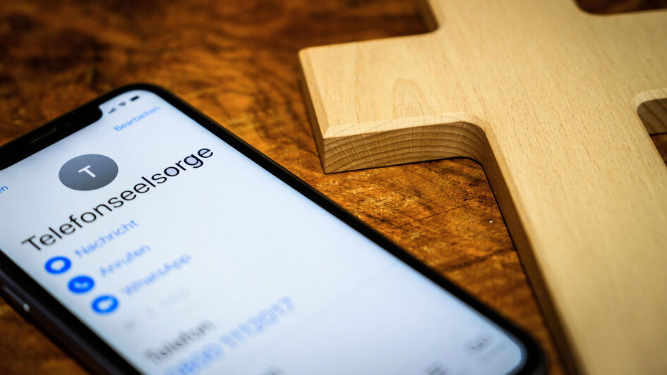 Handy und daneben liegendes Holzkreuz Handy und daneben liegendes Holzkreuz