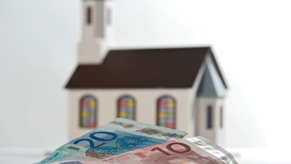 Kirche im Hintergrund, im Vordergrund Geldscheine