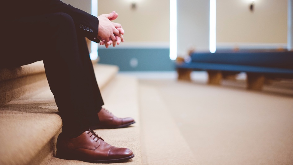 Mann sitzt betend in einer leeren Kirche