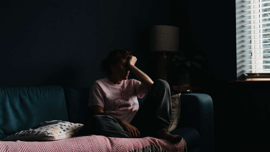 Einsam: Eine Frau sitzt allein in einem dunklen Zimmer