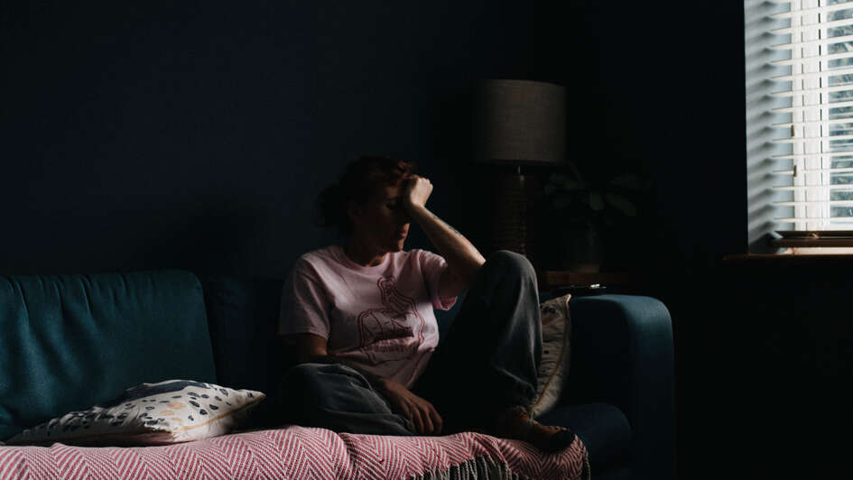 Einsam: Eine Frau sitzt allein in einem dunklen Zimmer Einsam: Eine Frau sitzt allein in einem dunklen Zimmer