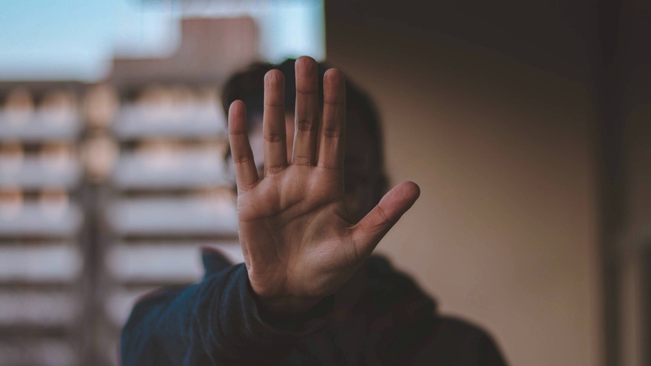 Person hält eine Hand abwehrend vor sich