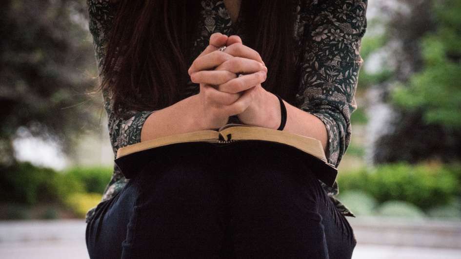 Eine Frau betet mit gefalteten Händen