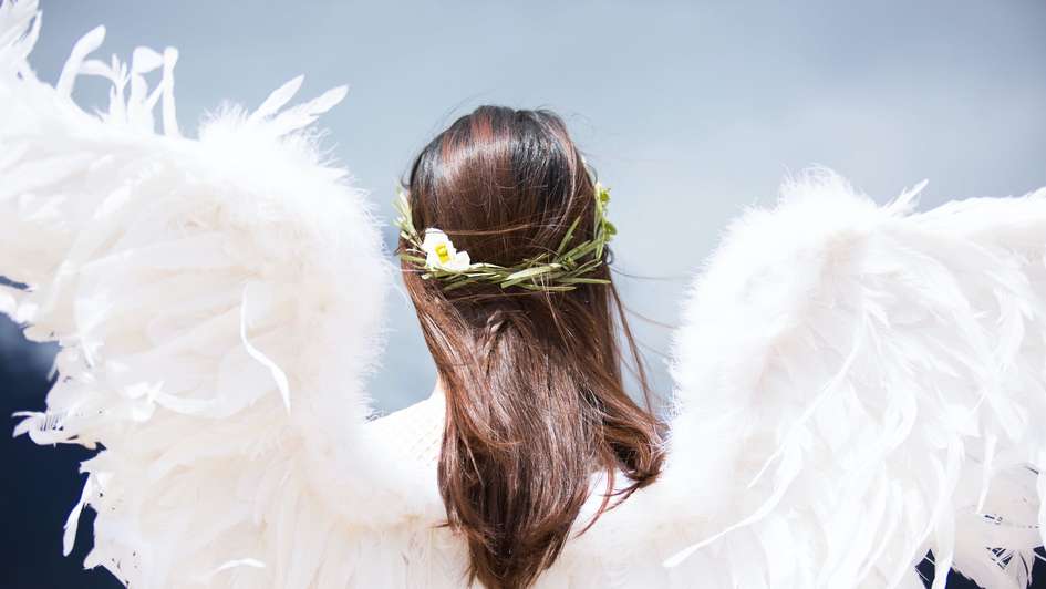 Ein Mädchen mit langen Haaren und Flügeln aus Federn Ein Mädchen mit langen Haaren und Flügeln aus Federn