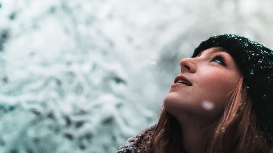 Eine junge Frau freut sich über Schneeflocken
