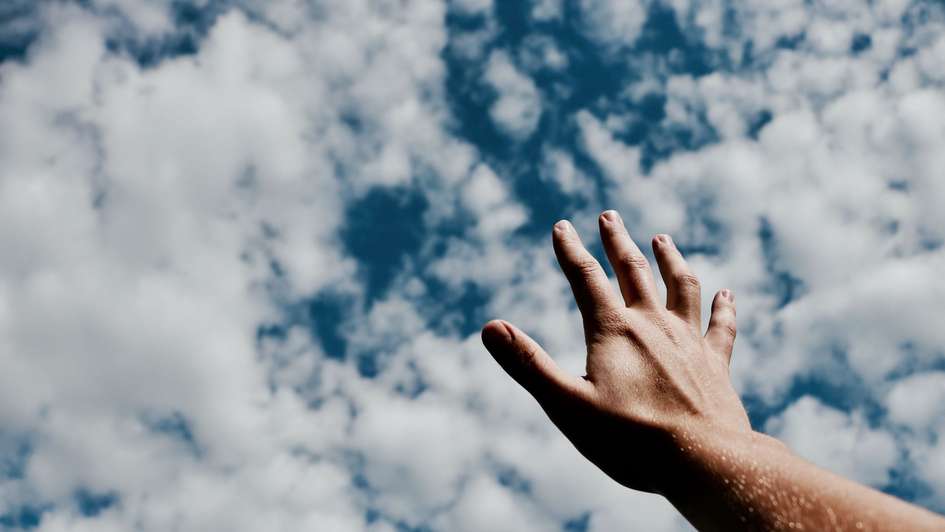 Eine Hand streckt sich zum Himmel