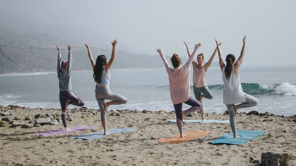 Menschen am Strand machen Yoga