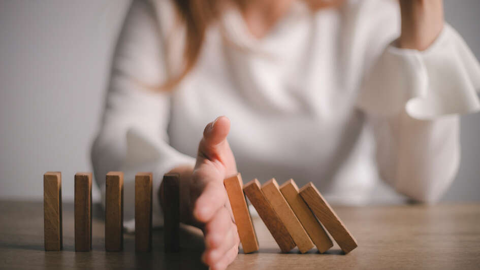 Symbolbild: Hand schützt Dominosteine vor dem Umfallen Symbolbild: Hand schützt Dominosteine vor dem Umfallen
