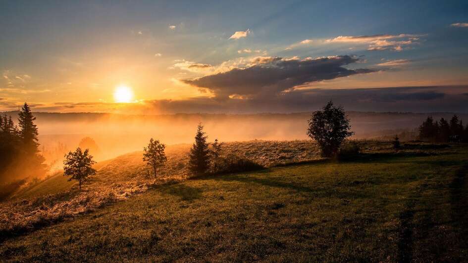 Aufgehende Sonne über einer Hügellandschaft Aufgehende Sonne über einer Hügellandschaft