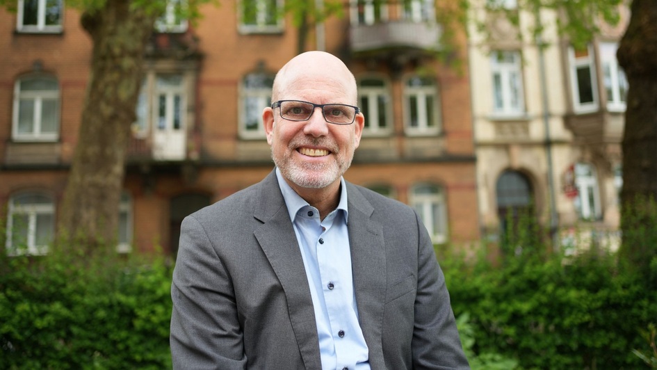 Pfarrer Joachim Baier aus Kassel, Portrait vor Allee und Altstadthäusern