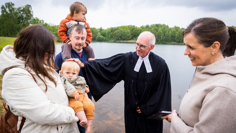 Pastor Martin Steinke tauft einen kleinen Jungen im Attersee Osnabrück