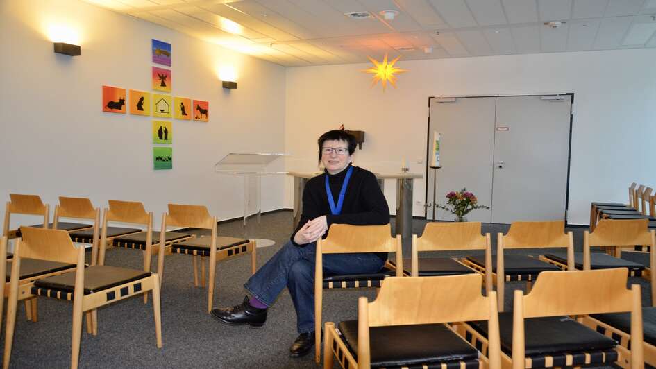 Bettina Kluenemann ist Flughafenseelsorgerin. Die 60jaehrige sitzt im Kirchenraum am Flughafen. Im Hintergrund ist ein Altar zu erkennen