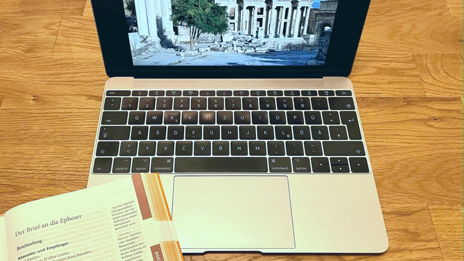 Aufgeklappter Laptop mit einer Bibel, die neben der Tastatur liegt. Auf dem Bildschirm ist ein Bild von Ruinen mir griechischen Säulen zu sehen. Die Bibel sit beim Epheserbrief aufgeschlagen. Aufgeklappter Laptop mit einer Bibel, die neben der Tastatur liegt. Auf dem Bildschirm ist ein Bild von Ruinen mir griechischen Säulen zu sehen. Die Bibel sit beim Epheserbrief aufgeschlagen.