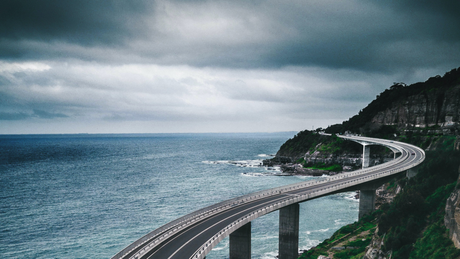 Sea Cliff Bridge, Clifton, Australien. Eine Autobrücke aus Beton an der grün bewachsenen Steilküste.