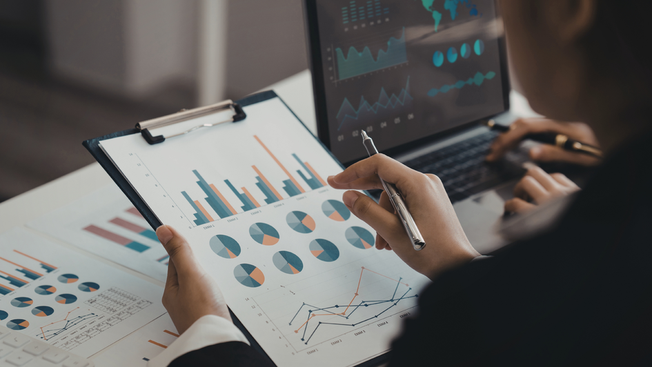 Mann mit Diagrammen in der Hand und Laptop