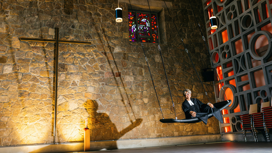 Pfarrerin Gabriele Hartlieb auf der Himmelsschaukel in der Kirche St.Thomas in Freiburg (Foto vom 20.10.2025). Sanft schwingt die Schaukel im weiten Raum hin und her. Ein leichter Lufthauch streicht um die Nase, waehrend man bequem in der Schaukel liegt,