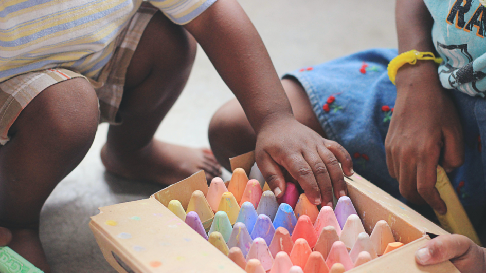 Kinder vor einer Kiste mit bunter Straßenkreide Kinder vor einer Kiste mit bunter Straßenkreide