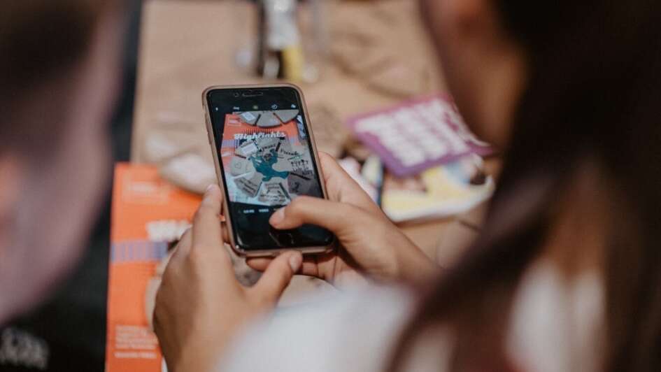 Mensch macht ein Handyfoto von einem Tisch mit Kreativ-Materialien Mensch macht ein Handyfoto von einem Tisch mit Kreativ-Materialien