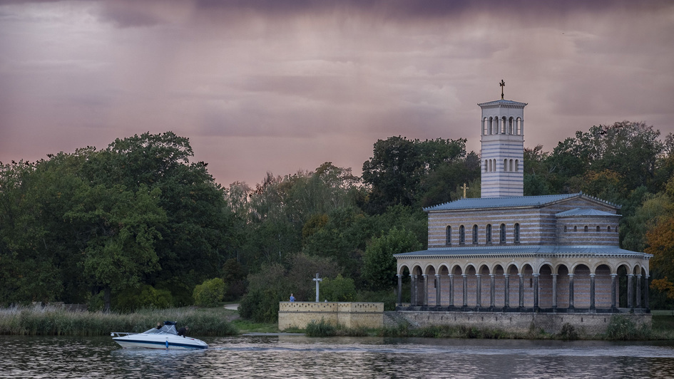 Die Heilandskirche Sacrow bei Potsdam an der Havel im Morgenrot vom Fluss aus gesehen