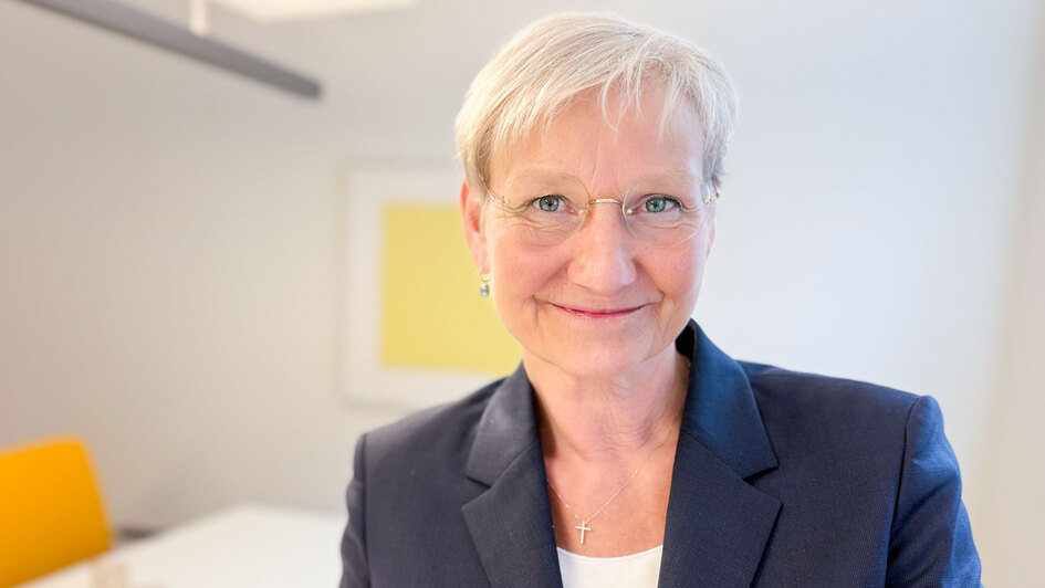 Kirsten Fehrs steht in einem Raum vor einem gelben Bild und hält die Osterbotschaft