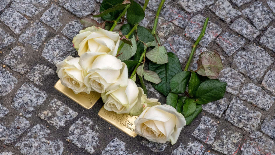 'Stolpersteine' bedeckt mit gelben Rosen