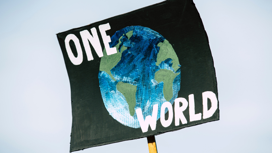 Symbolbild - Klimawandel: Schild mit einem Bild der Erde und der Aufschrift 'One World'
