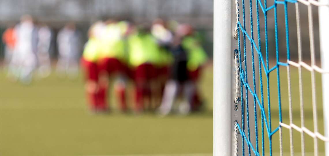 Ein Fußballtor, dahinter verschwommen einige Spieler