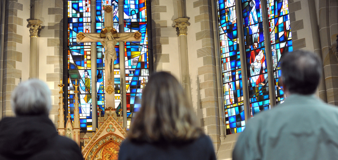 Drei Gottesdienstbesucher stehen vor dem Altar in der evangelisch-lutherischen Gartenkirche St. Marien in Hannover.
