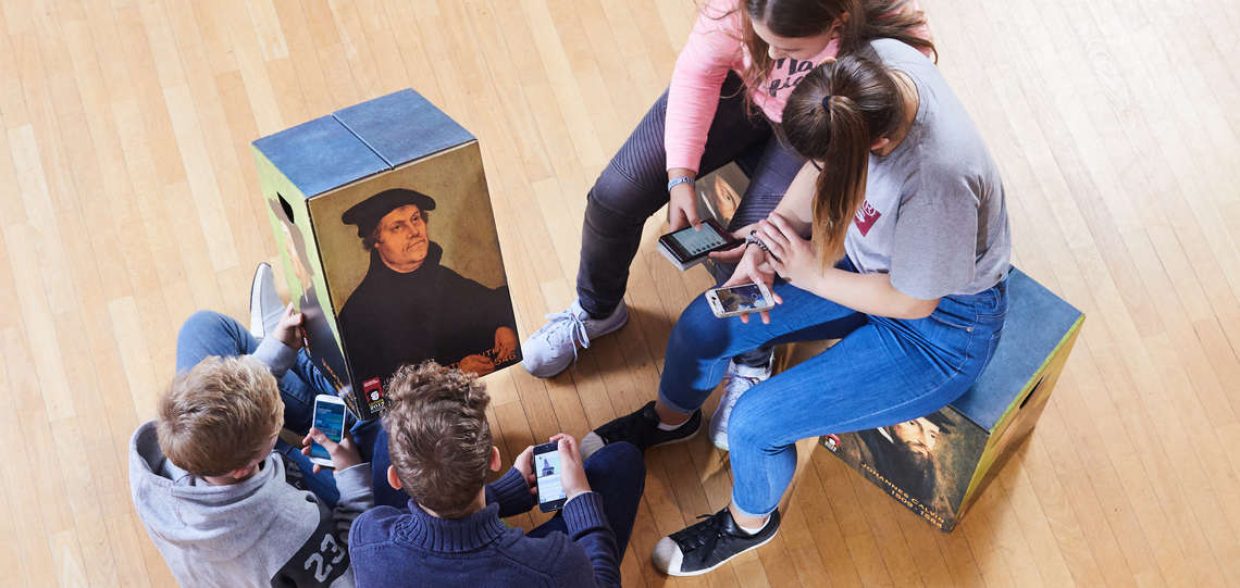 Vier Jugendliche betrachten ein Porträt von Martin Luther.