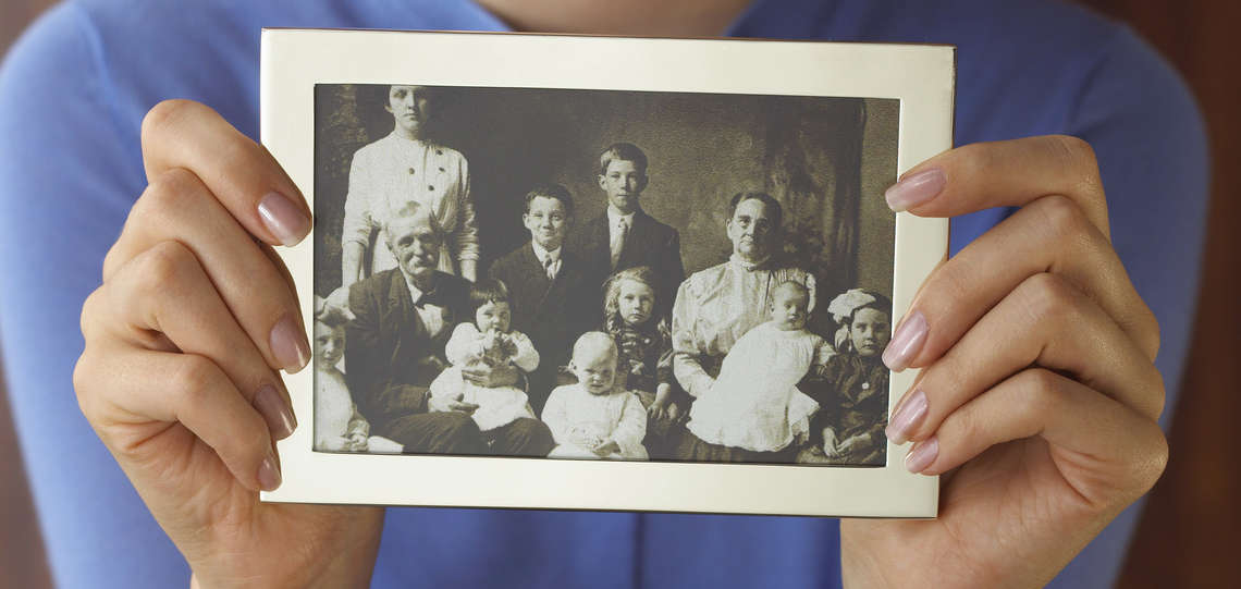 Nahaufnahme einer Frau, die ein altes Familienfoto in den Händen hält.