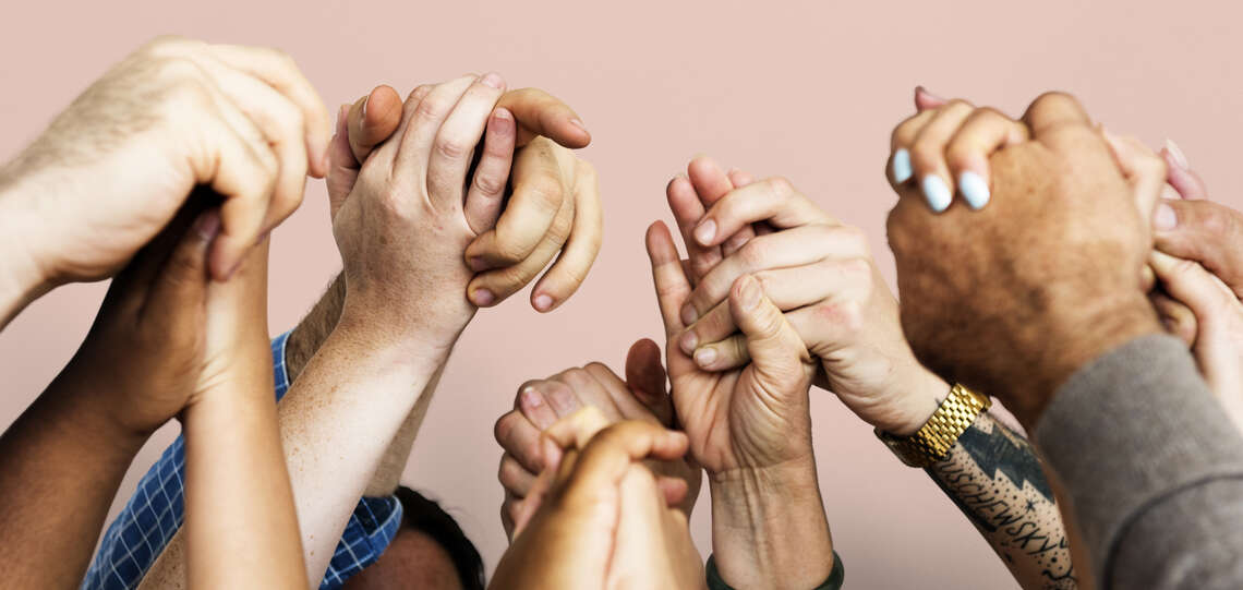 Eine Gruppe von Menschen hält sich an den Händen. Eine Gruppe von Menschen hält sich an den Händen.