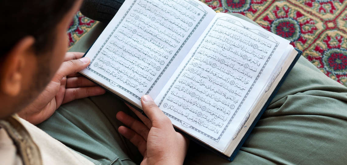 Ein junger Mann liest in einer Moschee im Koran.