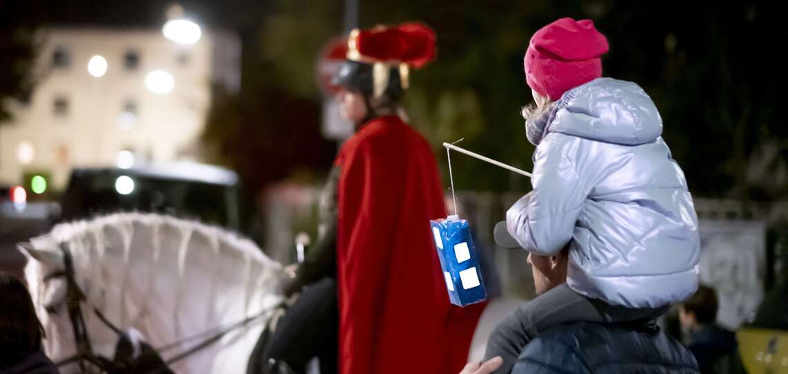 Kind mit Laterne auf den Schultern eines Mannes beim Martinsumzug
