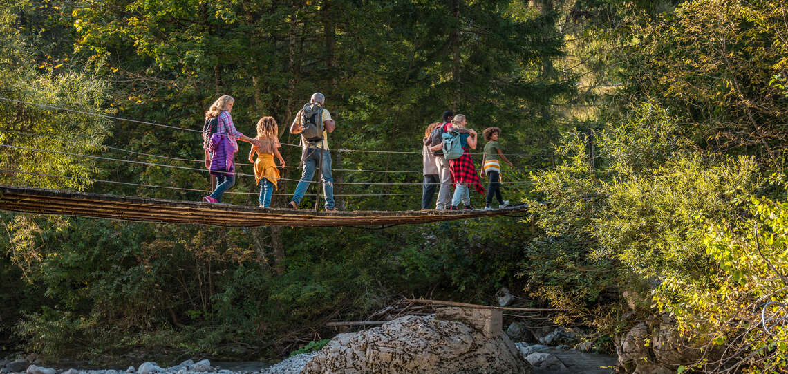 Symbolbild: Mehrgenerationen-Familie auf Waldbrücke über Fluss