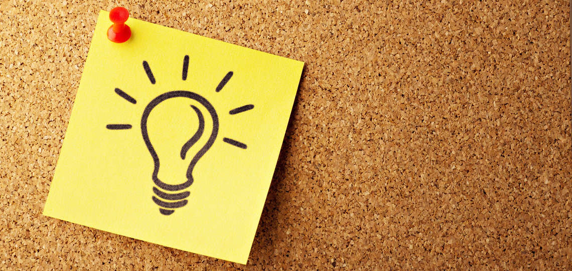 Postit mir Glühlampe auf einer Pinnwand Postit mir Glühlampe auf einer Pinnwand