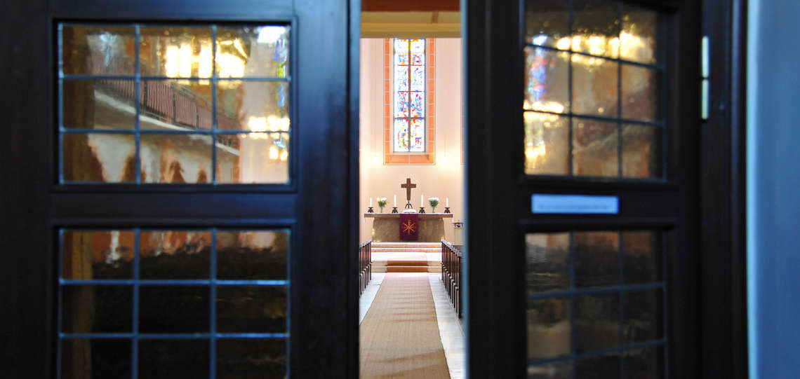 Blick in eine evangelische Kirche durch die geöffnete Tür Blick in eine evangelische Kirche durch die geöffnete Tür
