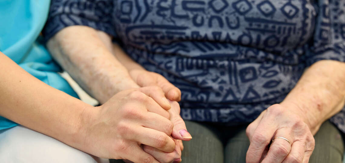 Themenbild Altenpflegeheimseelsorge: Pflegerin hält Bewohnerin die Hand Themenbild Altenpflegeheimseelsorge: Pflegerin hält Bewohnerin die Hand